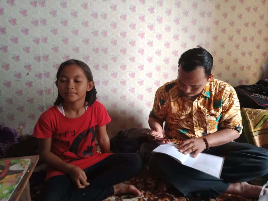 Pak Aleh, guru SDN 4 Ciseureh Kecamatan Purwakarta sedang memeriksa buku tugas muridnya dirumah orang tua murid yang dikunjunginya, Rabu (10/3/2021)